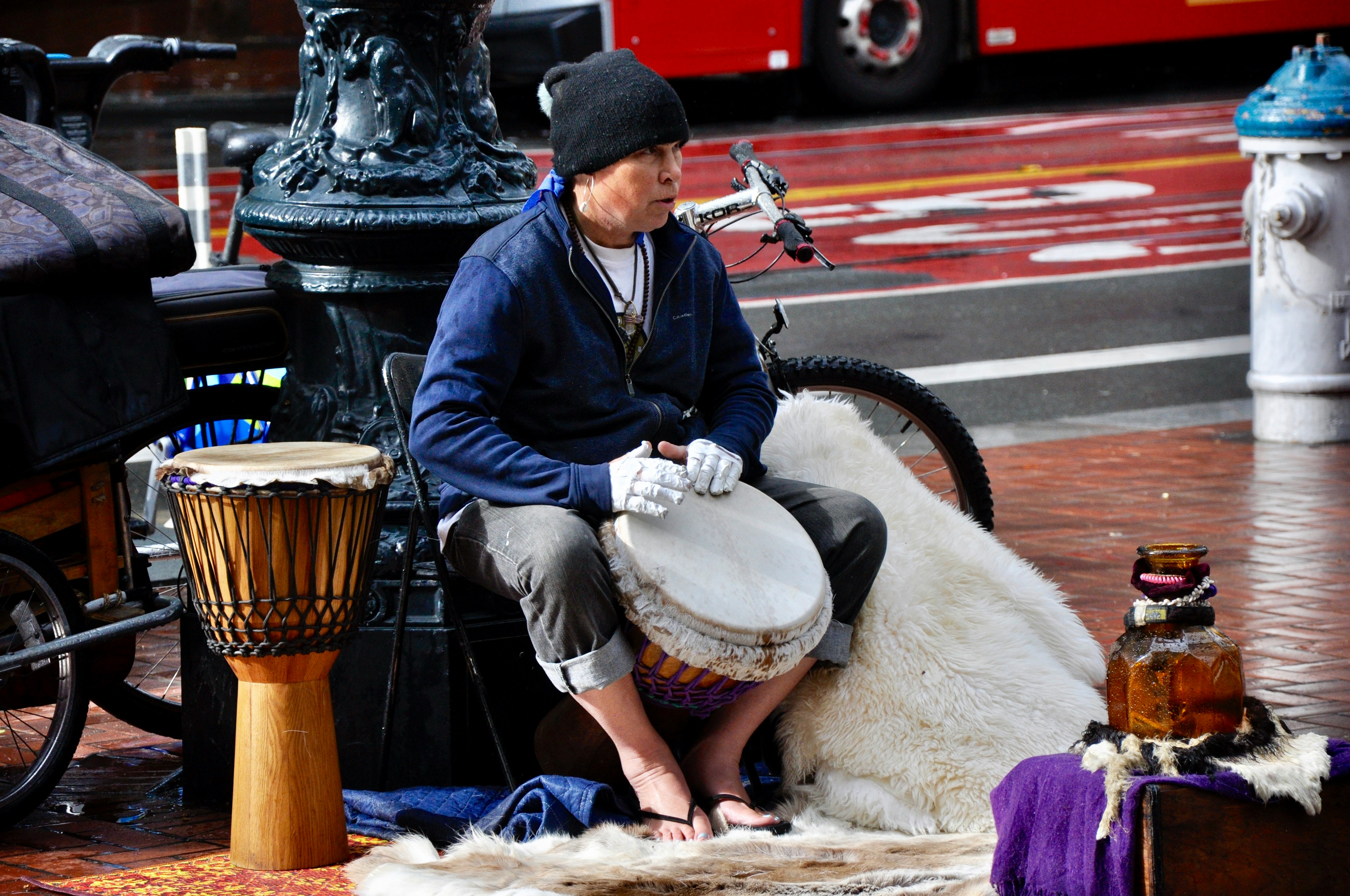 man in black jacket and blue denim jeans playing drum